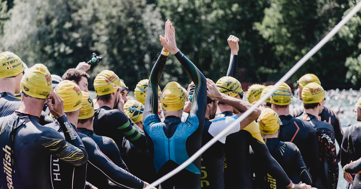 Groupe de triathlètes avec bonnets bleus et jaunes au départ de la nage